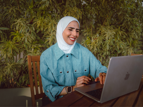 Arwa sitting with a cup of tea beside a plant